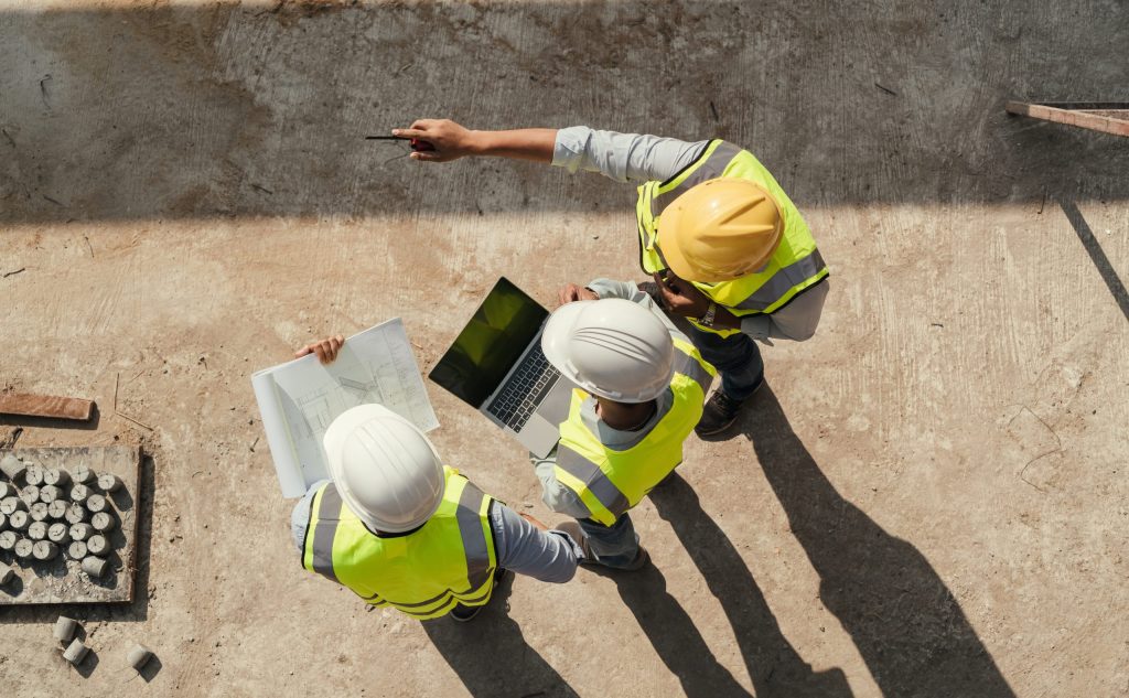 Birds eye view of a construction planning team using a laptop on-site